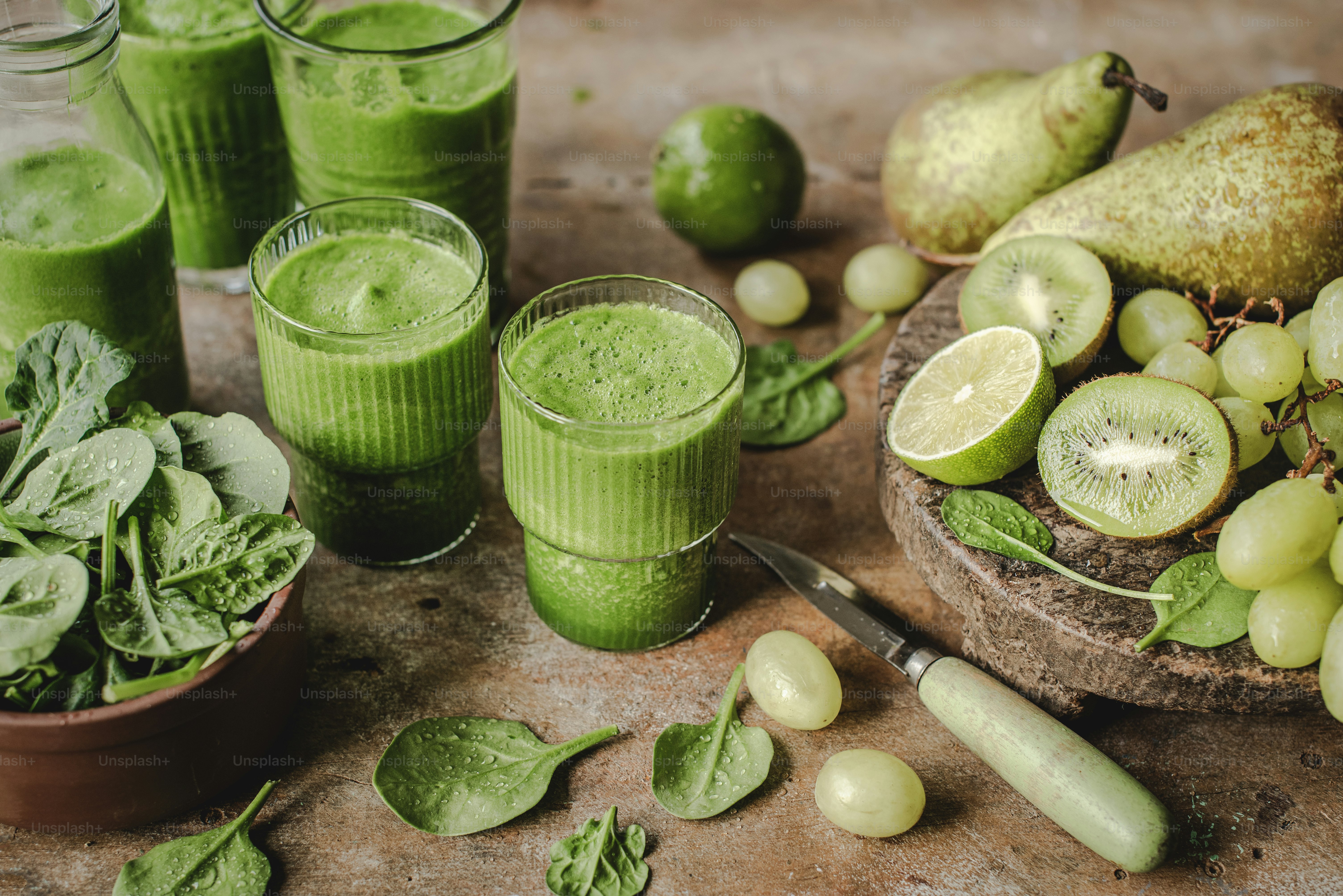 a table topped with glasses filled with green smoothies
