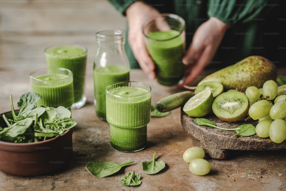 a table topped with glasses filled with green smoothies