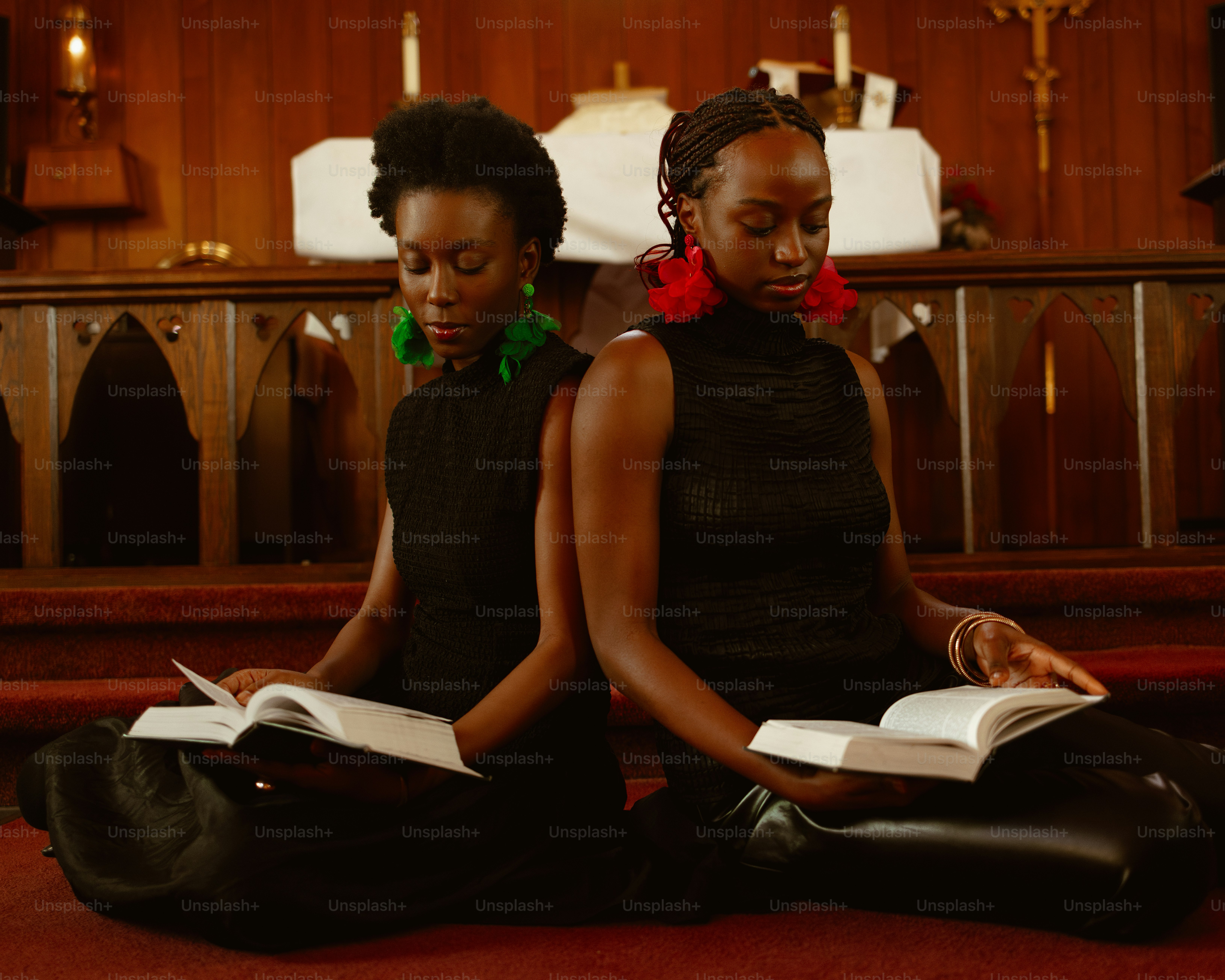 two women sitting on the floor reading a book