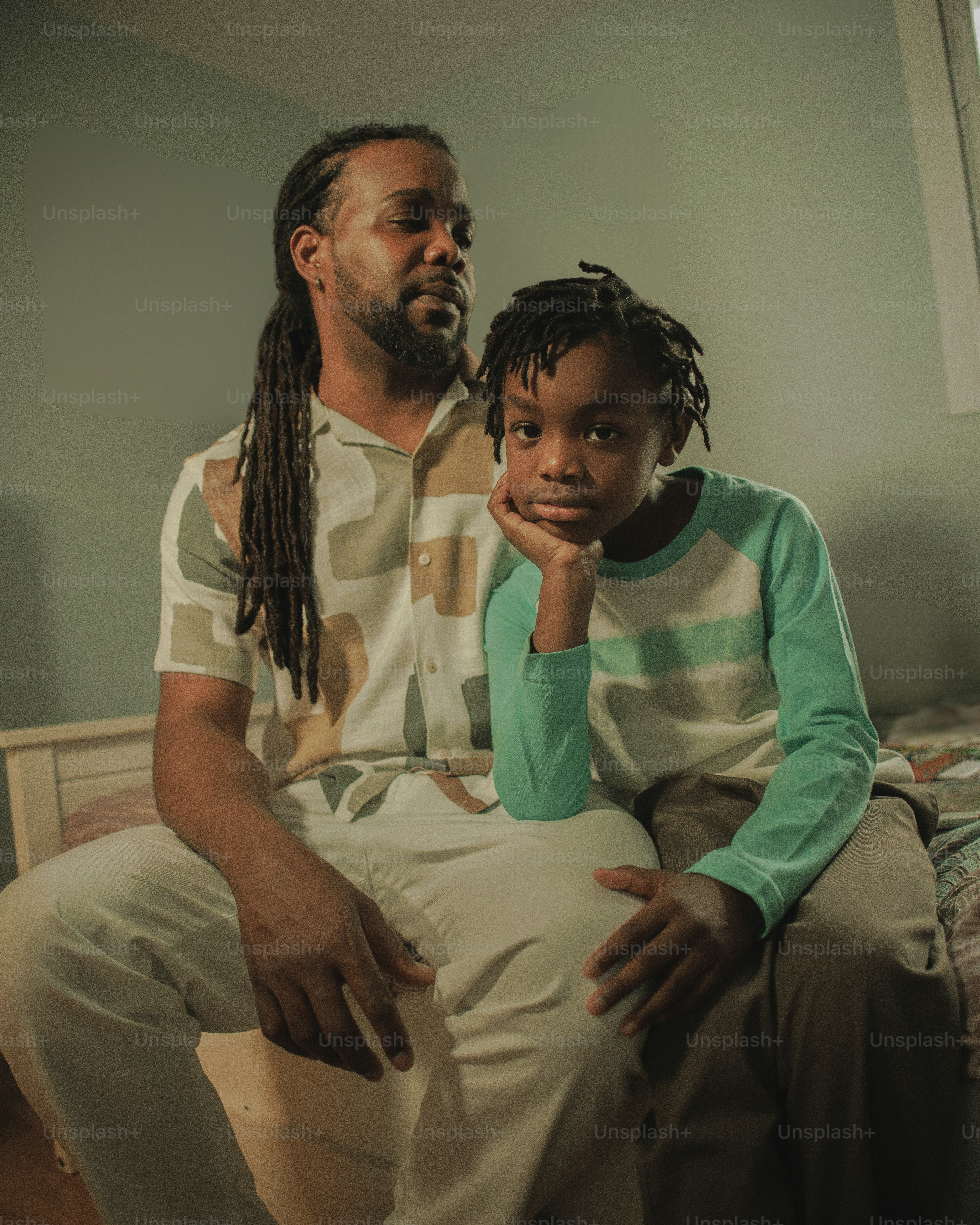 a man sitting next to a little girl on a bed