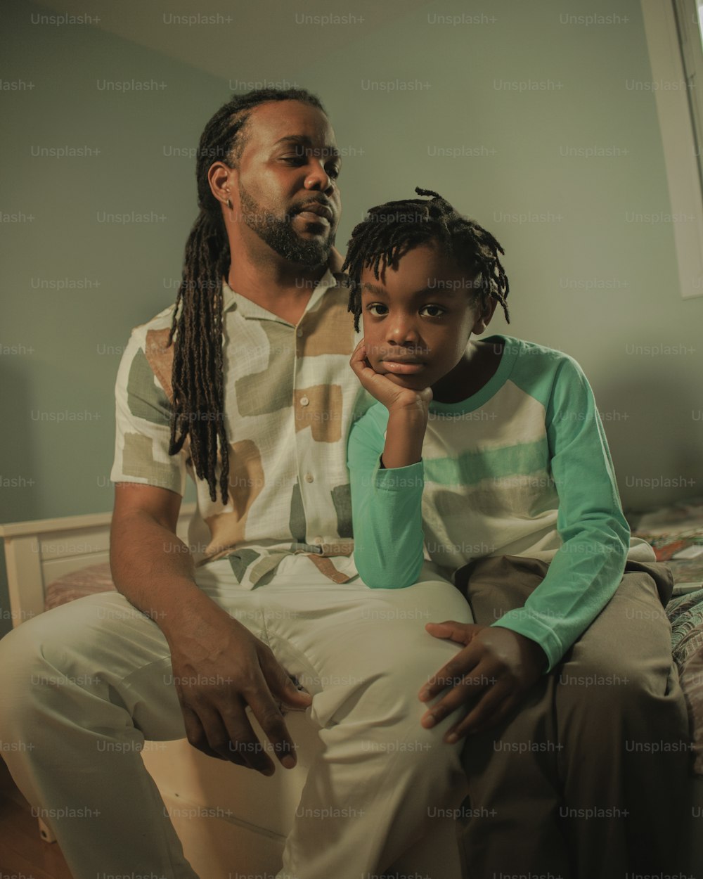 a man sitting next to a little girl on a bed