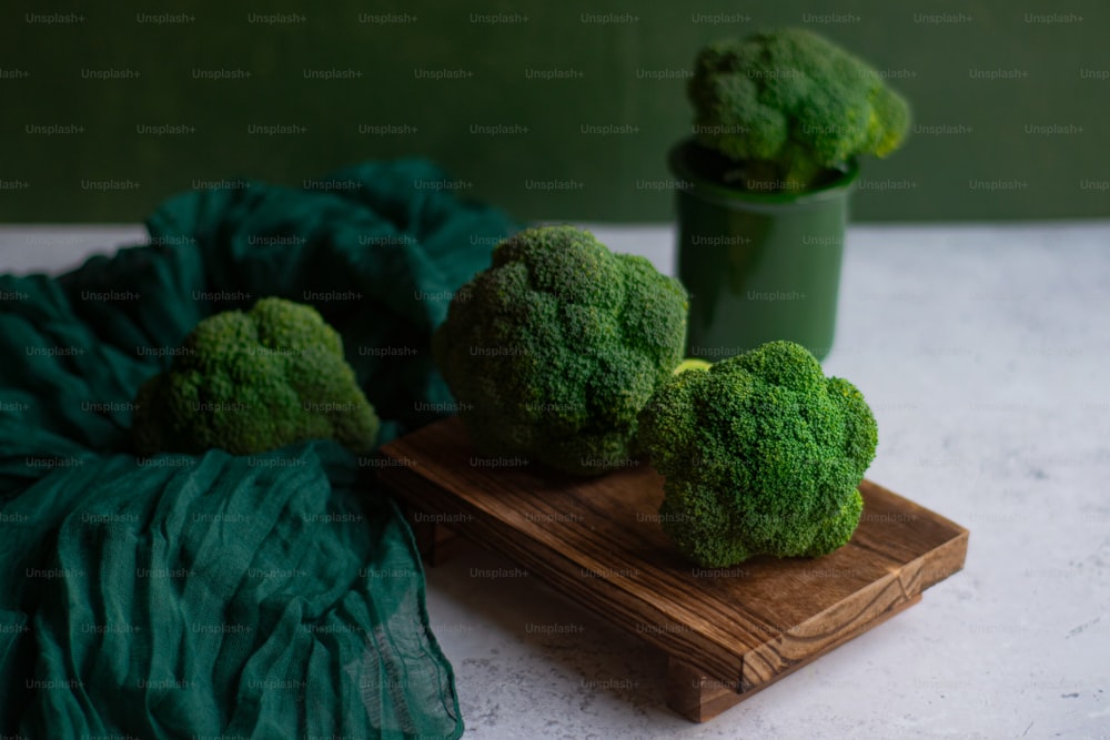 a wooden cutting board topped with broccoli on top of a table