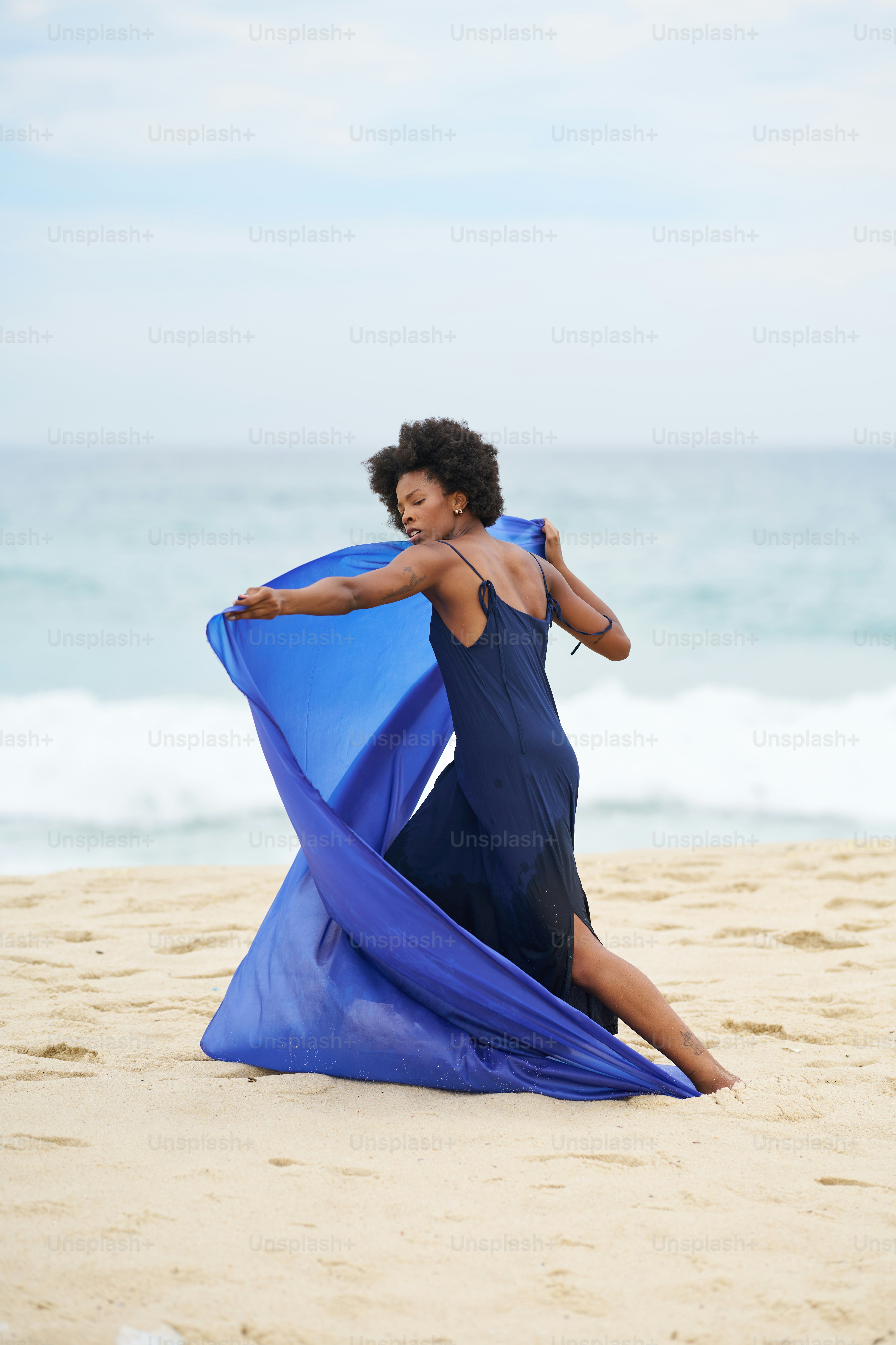 A woman in a blue dress is on the beach photo – Blue colour Image on ...