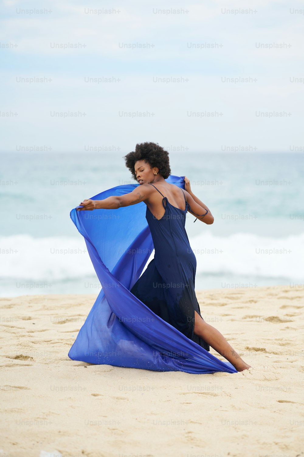 a woman in a blue dress on the beach