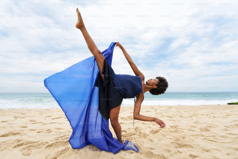 a woman in a blue dress on a beach
