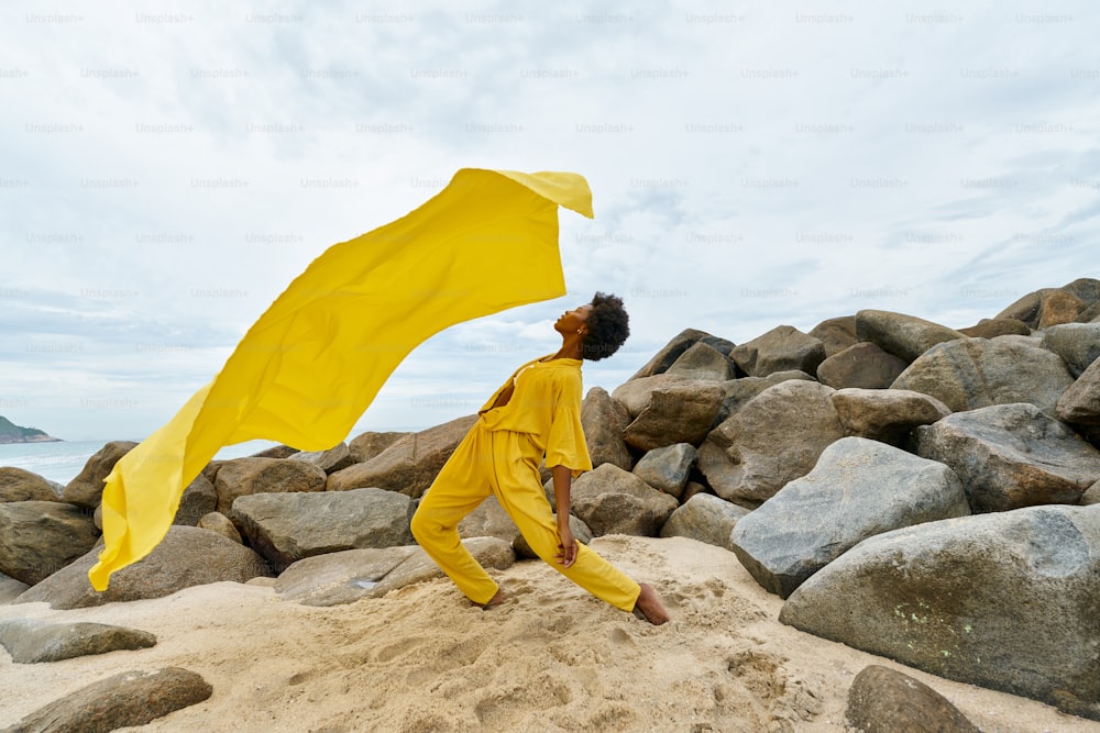a woman in a yellow outfit on a rocky beach