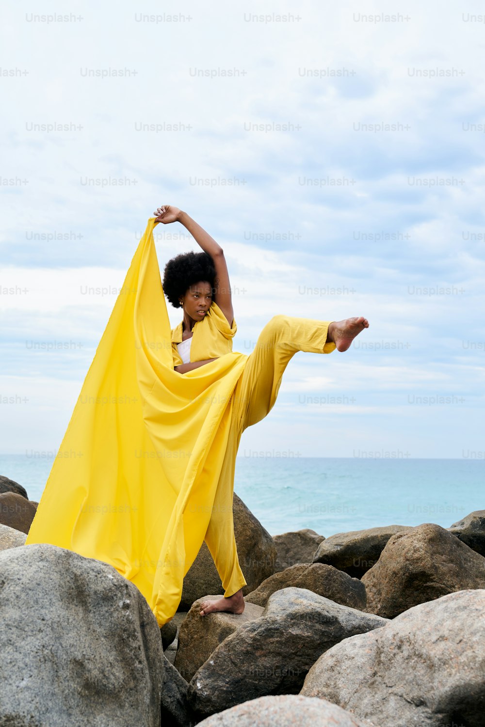 a woman in a yellow dress standing on rocks