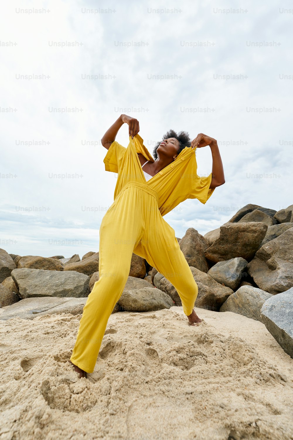 una mujer de pie en la cima de una playa de arena
