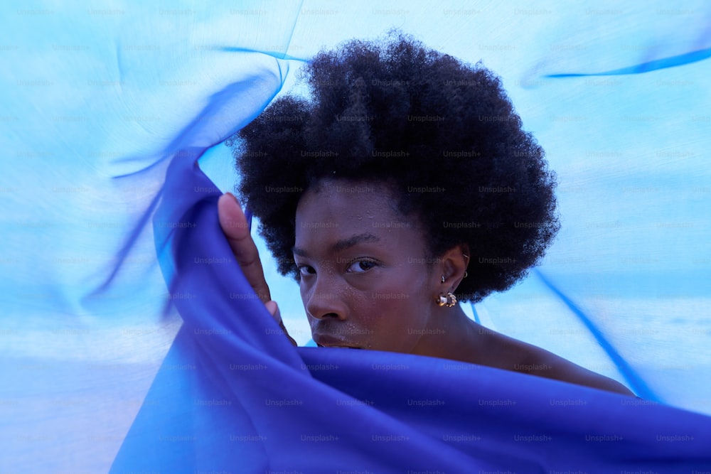 a woman with an afro holding a blue cloth
