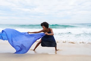 a woman is running on the beach with a blue cloth
