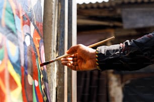 eine Person, die einen Pinsel hält und an einer Wand malt