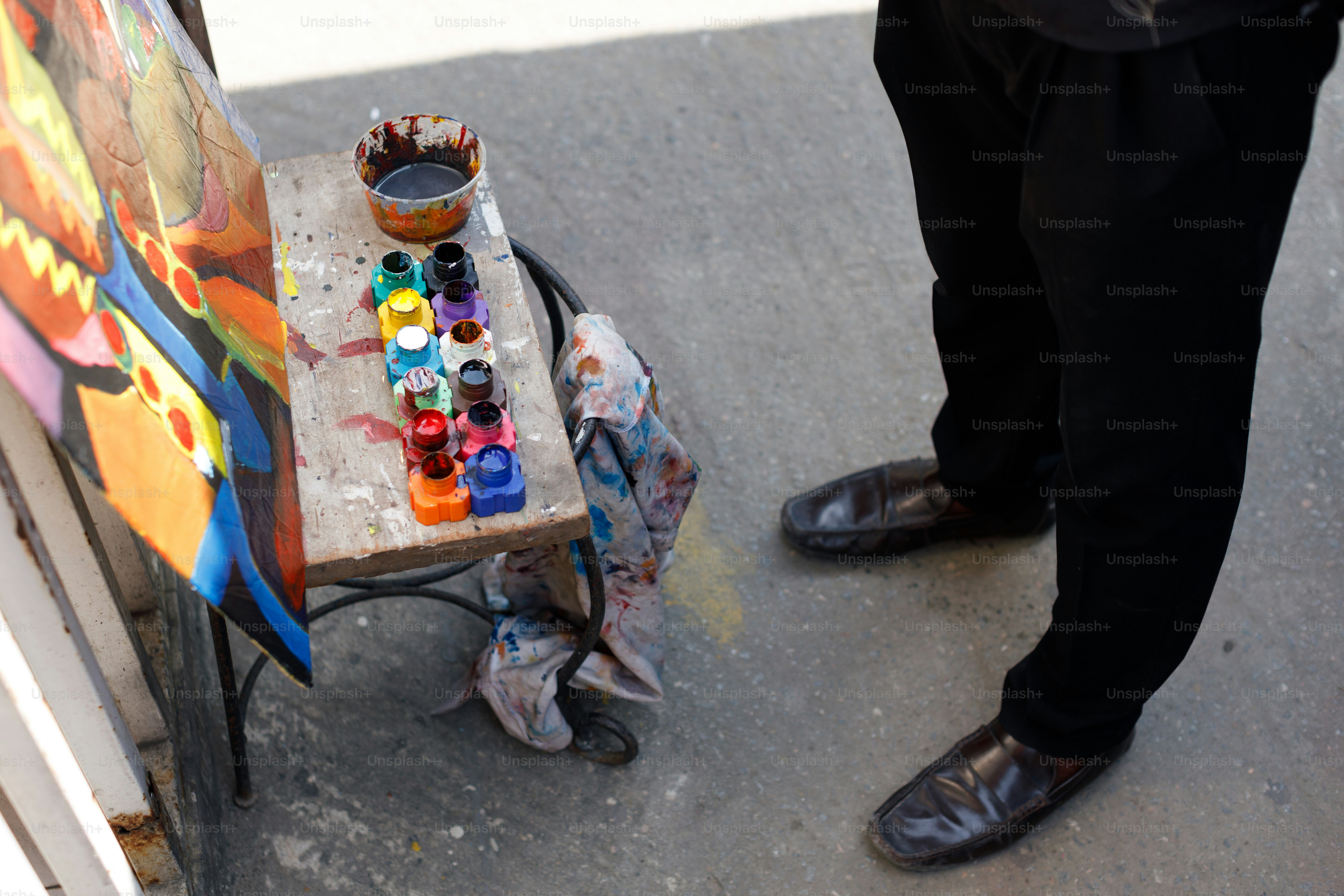 a man standing next to a table with a painting on it