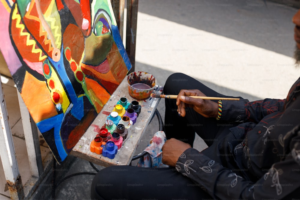 un hombre sentado en el suelo pintando con un pincel