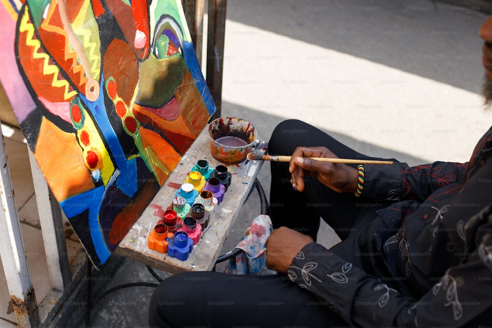 a man sitting on the ground painting with a brush