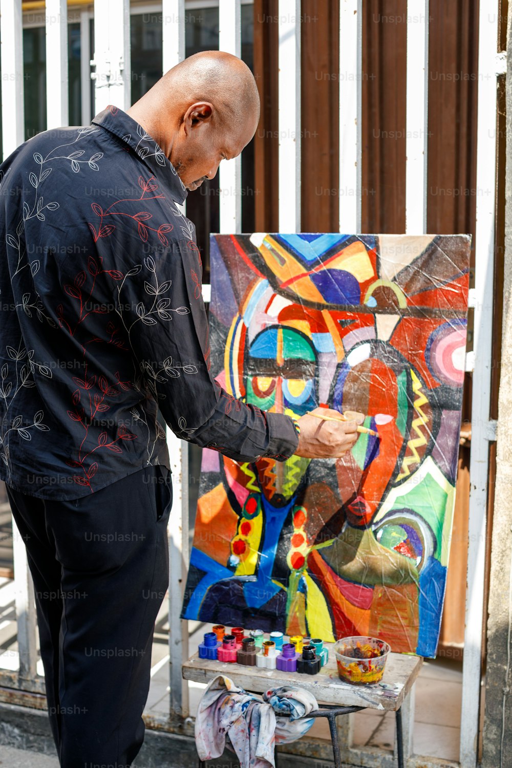 Un hombre de pie junto a una pintura en un caballete