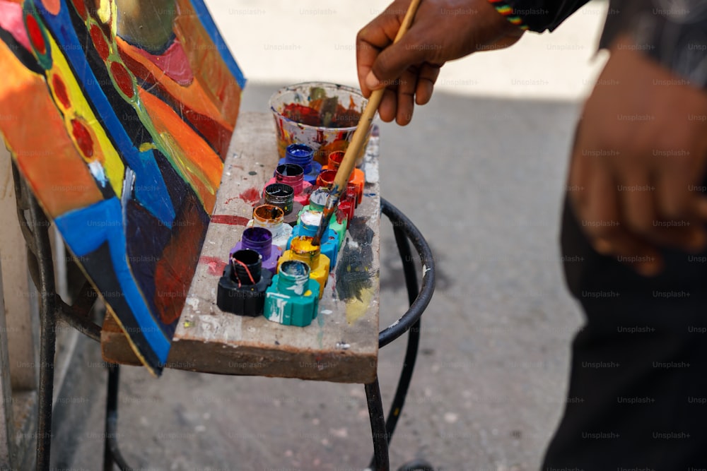 Un hombre sostiene un pincel y pinta sobre un lienzo