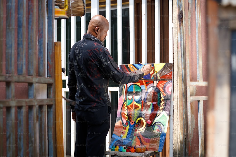 a man standing next to a painting on a easel