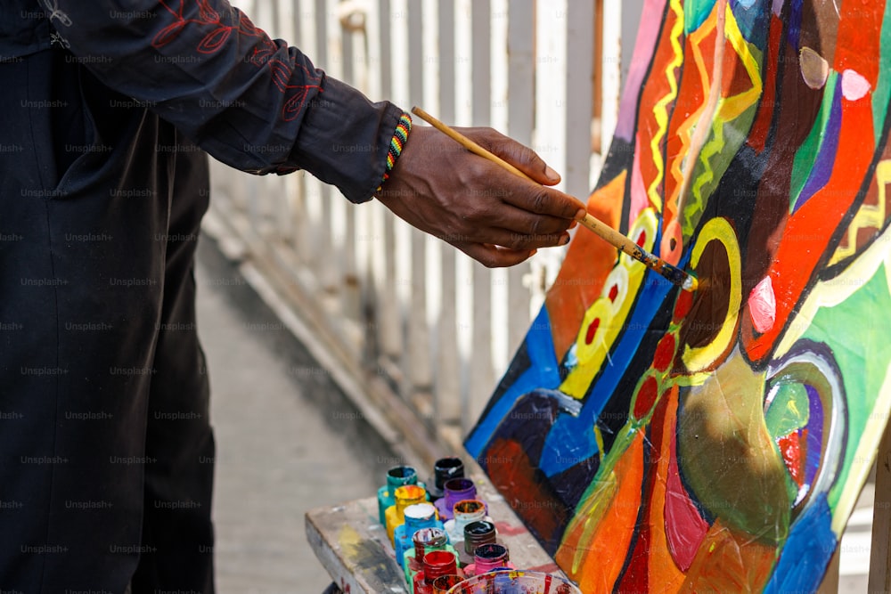 un hombre sosteniendo un pincel pintando una pared colorida