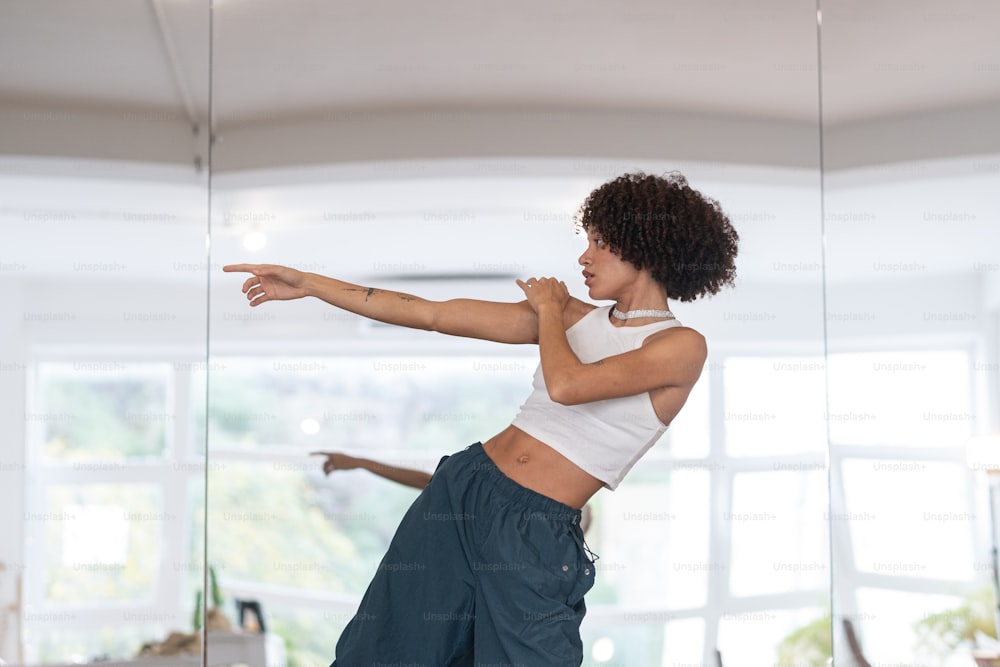 Una mujer con una camiseta blanca sin mangas está haciendo una postura de yoga