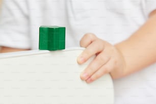 a child holding a green piece of wood