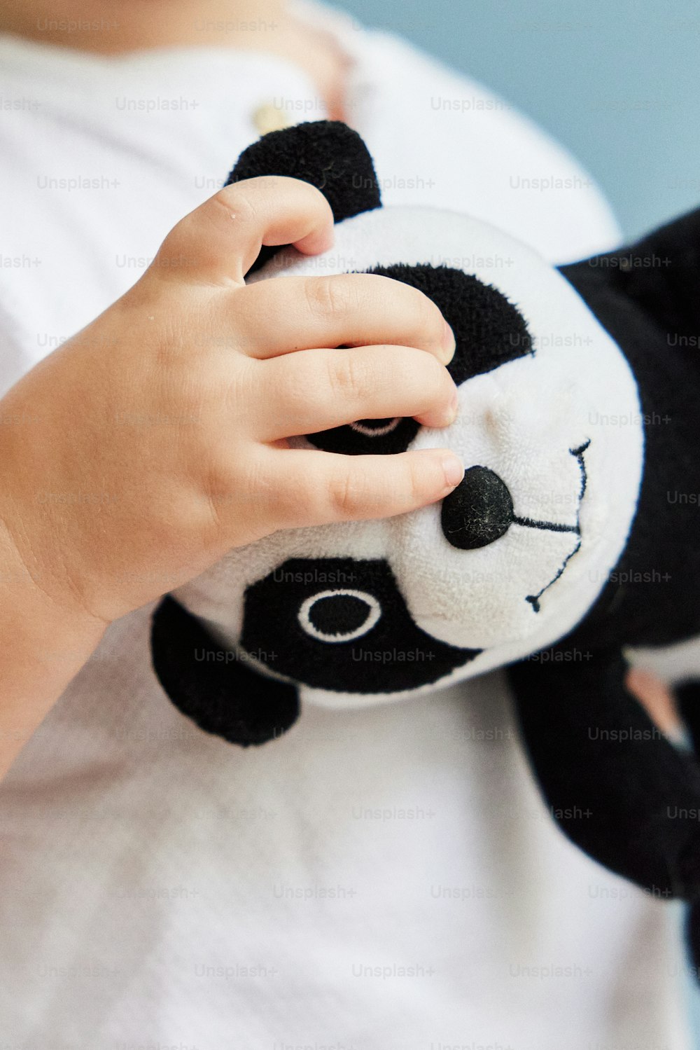 uma criança pequena segurando um urso panda de pelúcia