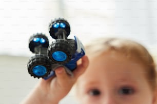 a little boy holding four toy trucks in his hand