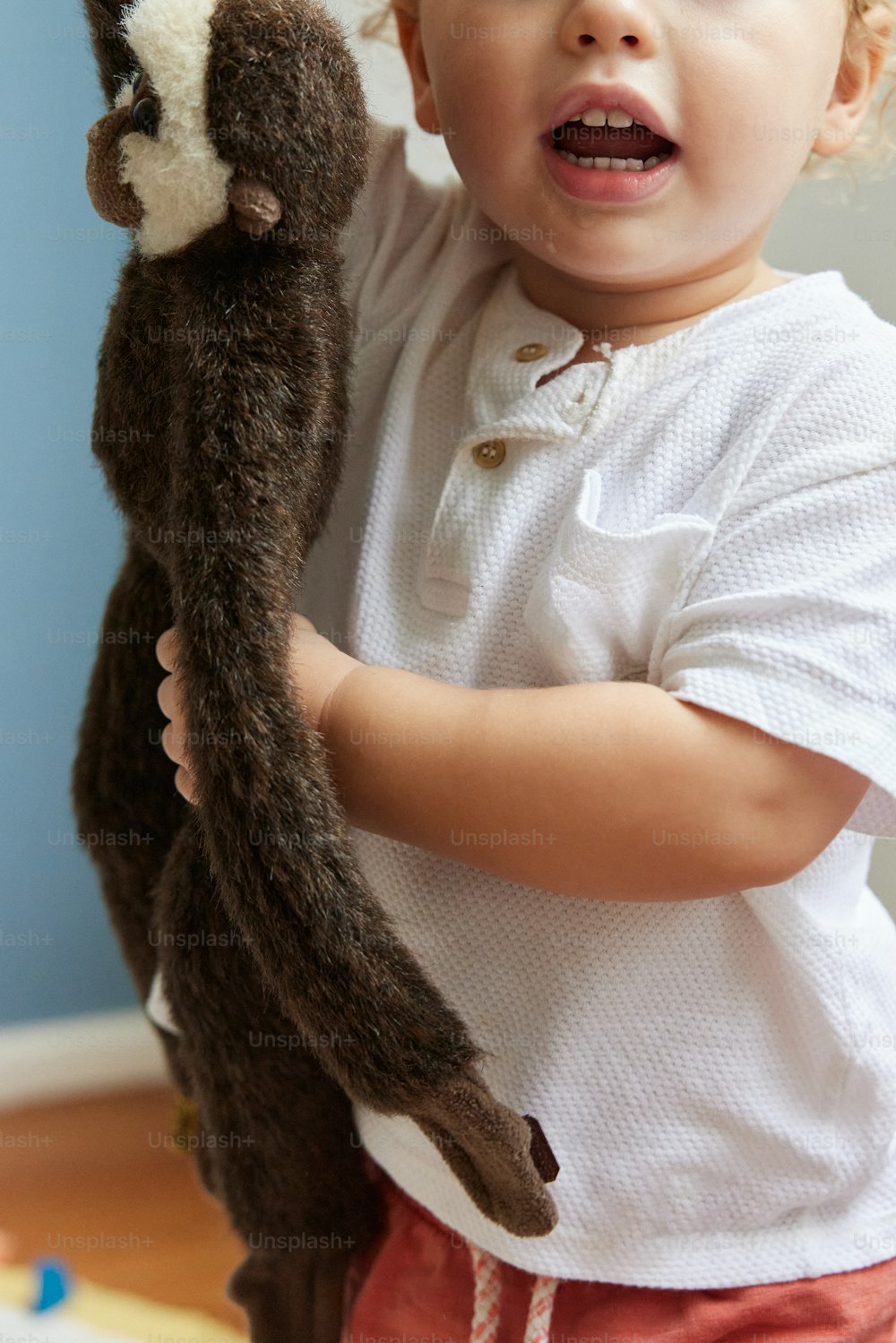 un petit garçon tenant un animal en peluche dans ses mains