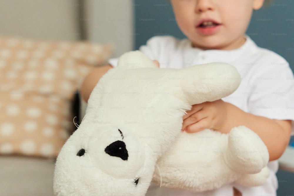a little boy holding a white teddy bear