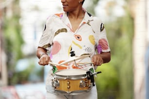 a woman playing a drum on the street