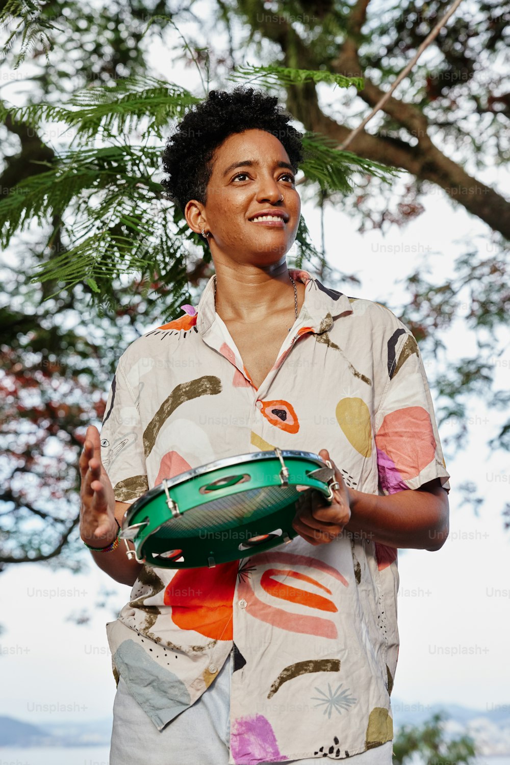 a man holding a green frisbee under a tree