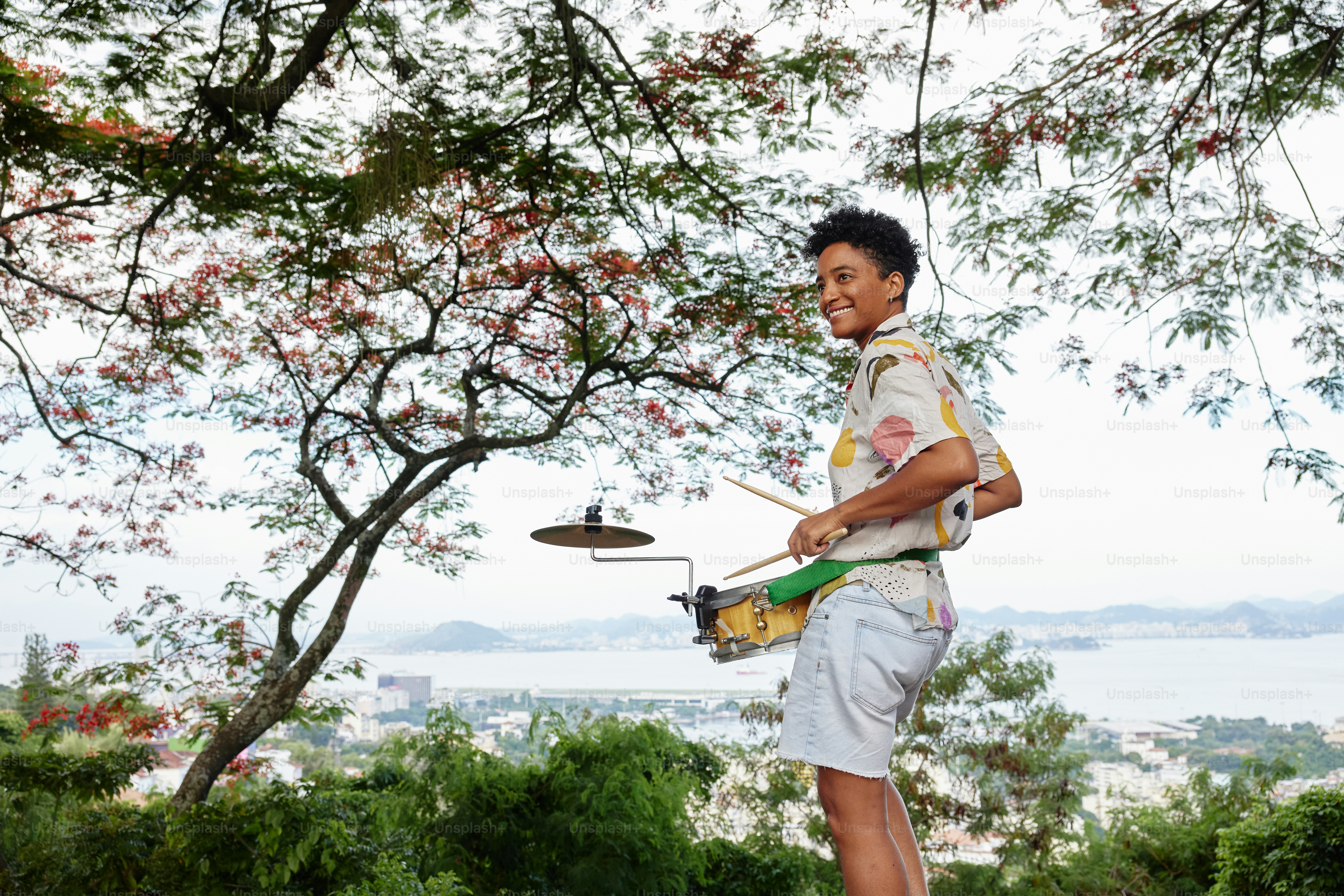 a young man playing a drum set under a tree