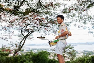 a young man playing a drum set under a tree