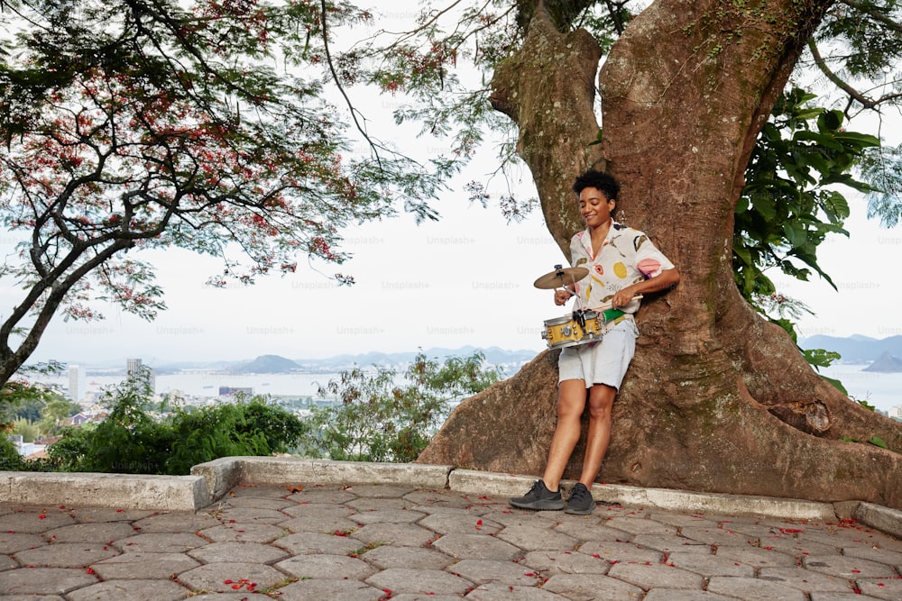 a man standing next to a tree holding a skateboard