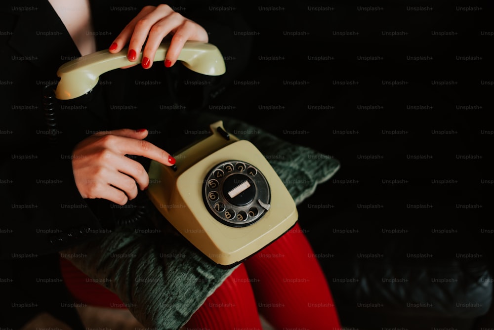 Eine Frau in roten Strümpfen hält ein gelbes Telefon in der Hand