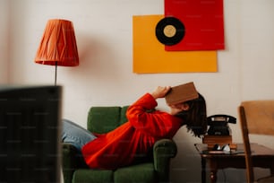 una donna seduta su un divano con una scatola in testa