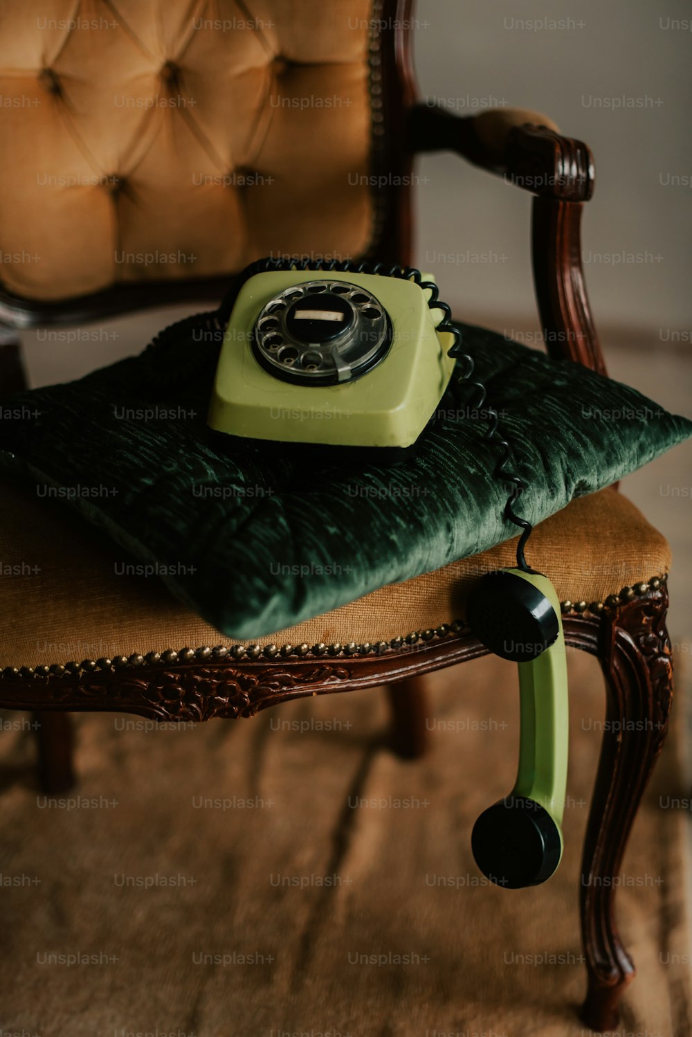um telefone verde sentado em cima de uma almofada em uma cadeira