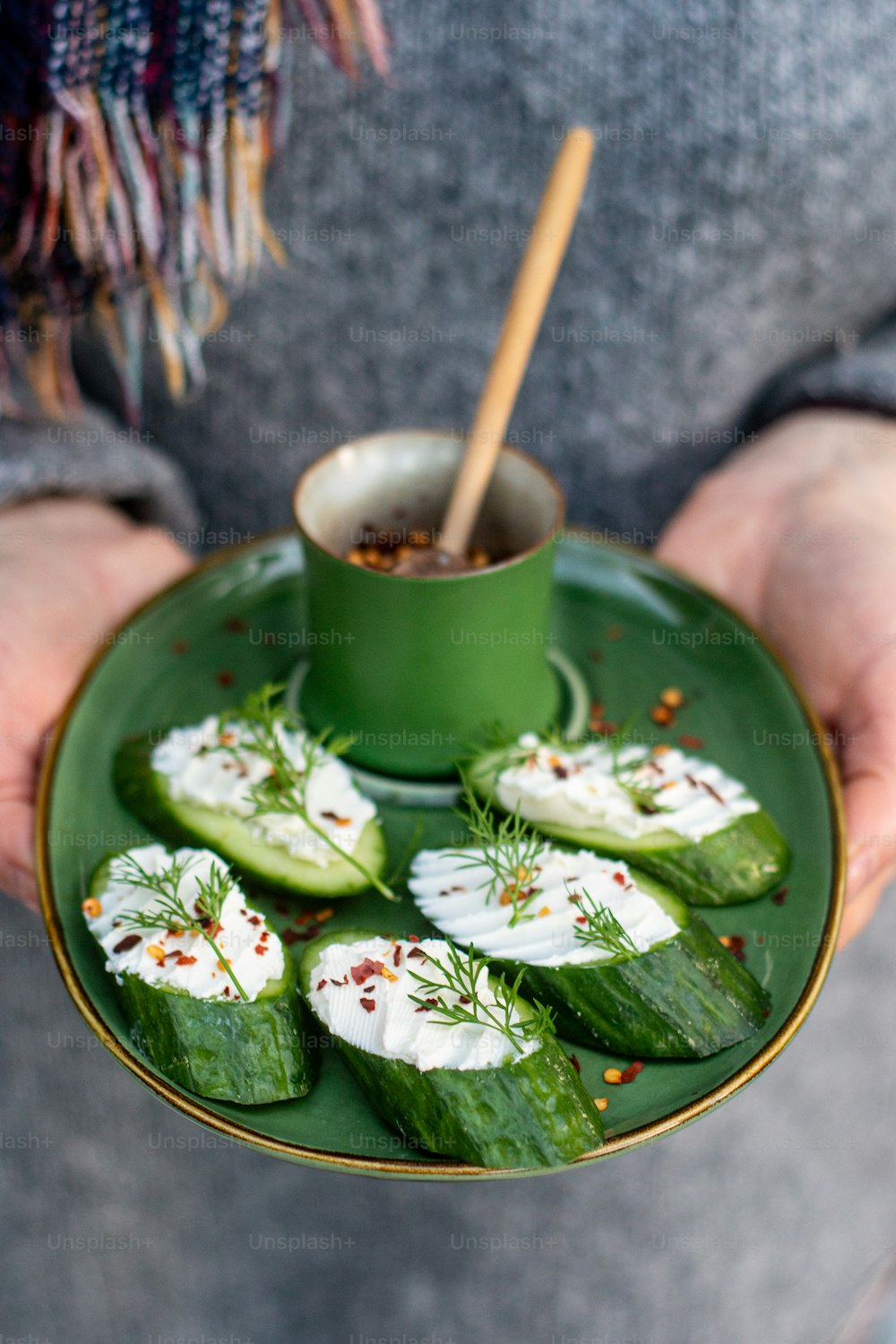 a person holding a green plate with cucumbers on it