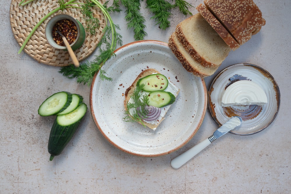 a plate with a sandwich and some cucumbers on it