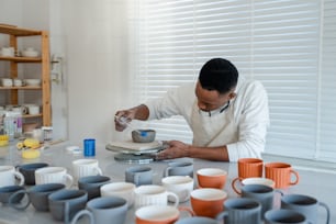 a man in a white shirt and some cups on a table