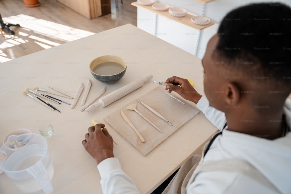 ein Mann sitzt an einem Tisch und arbeitet an einem Kunstwerk