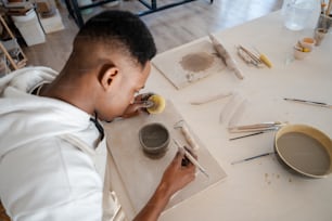 Um homem está pintando um quadro em uma mesa