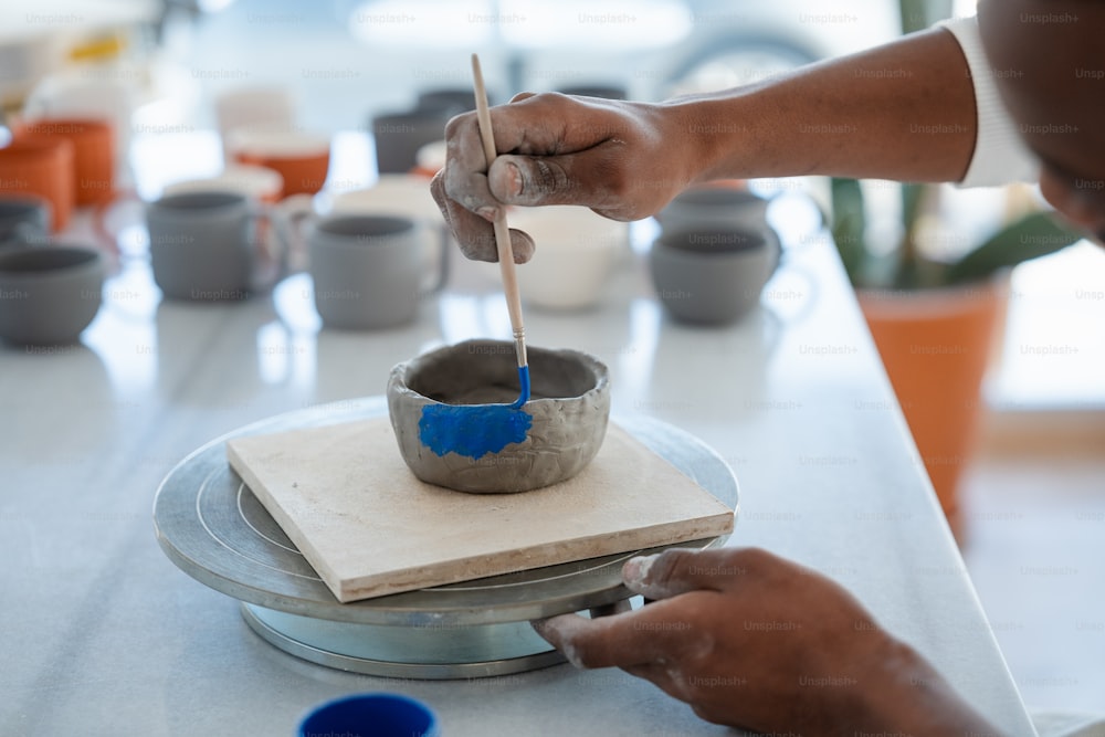 a person is painting a bowl on a table