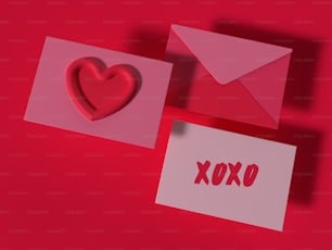 um envelope vermelho com um coração e um cartão com a palavra xoxo