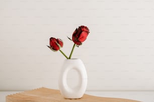 un vaso bianco con tre rose rosse