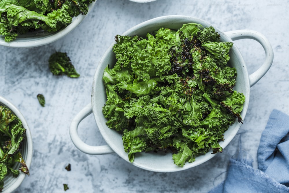 three bowls of cooked broccoli on a table