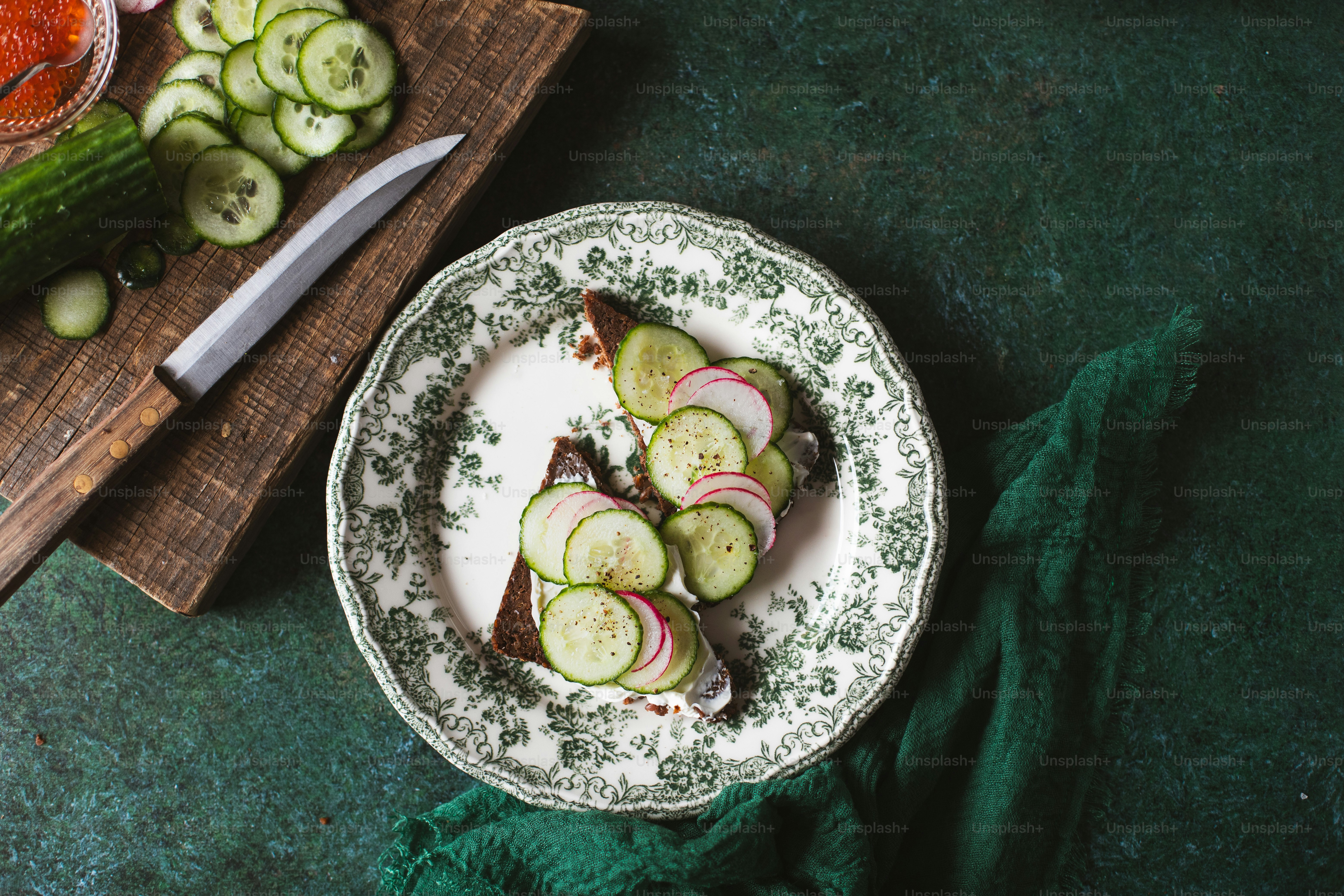 a plate of sliced cucumbers and a knife on a cutting board
