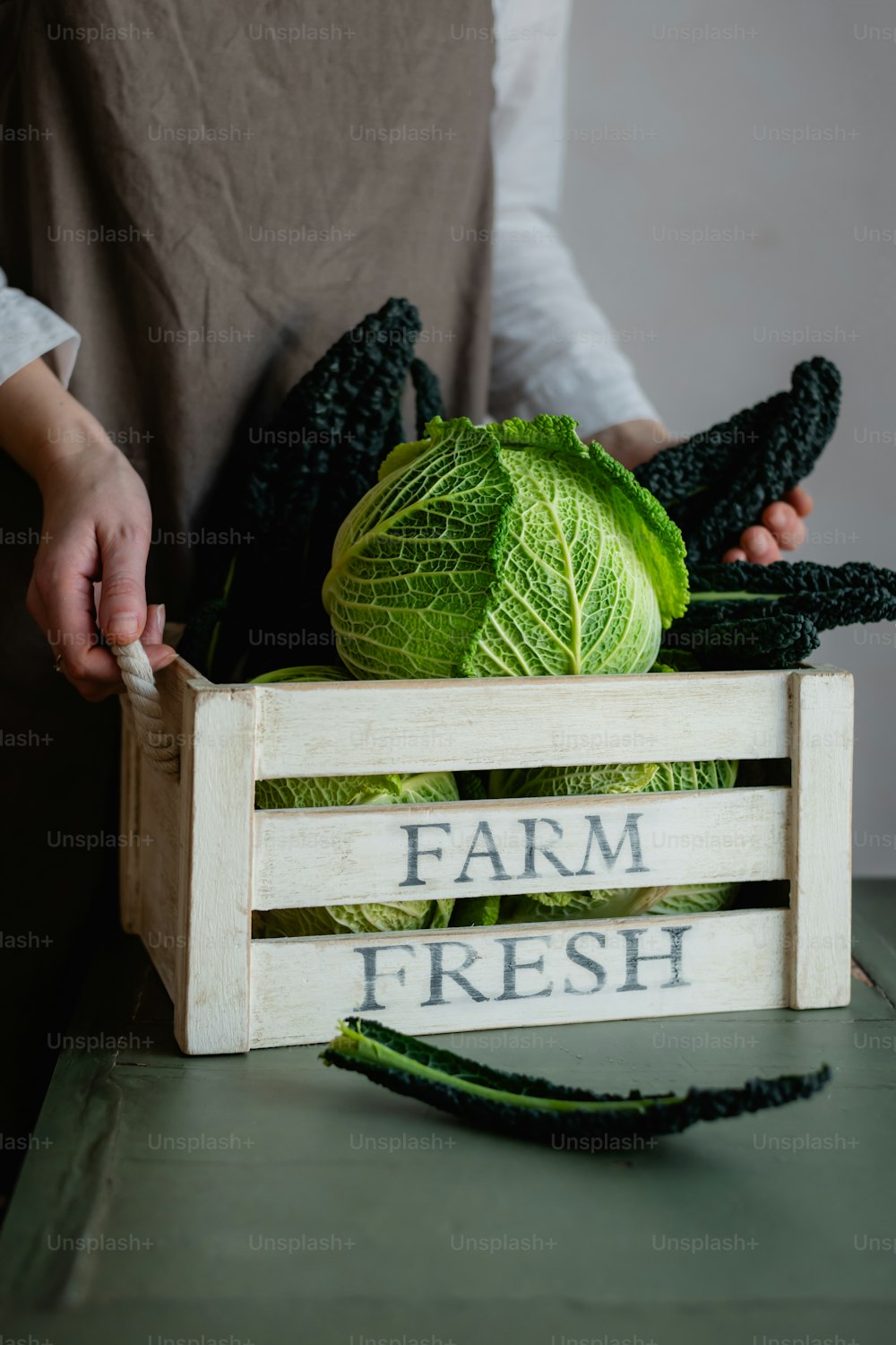 a person holding a wooden crate filled with cabbage