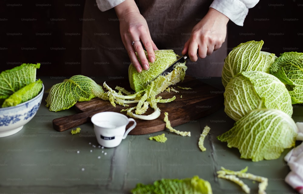 a person cutting cabbage on a cutting board