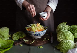 a person in an apron is preparing a salad