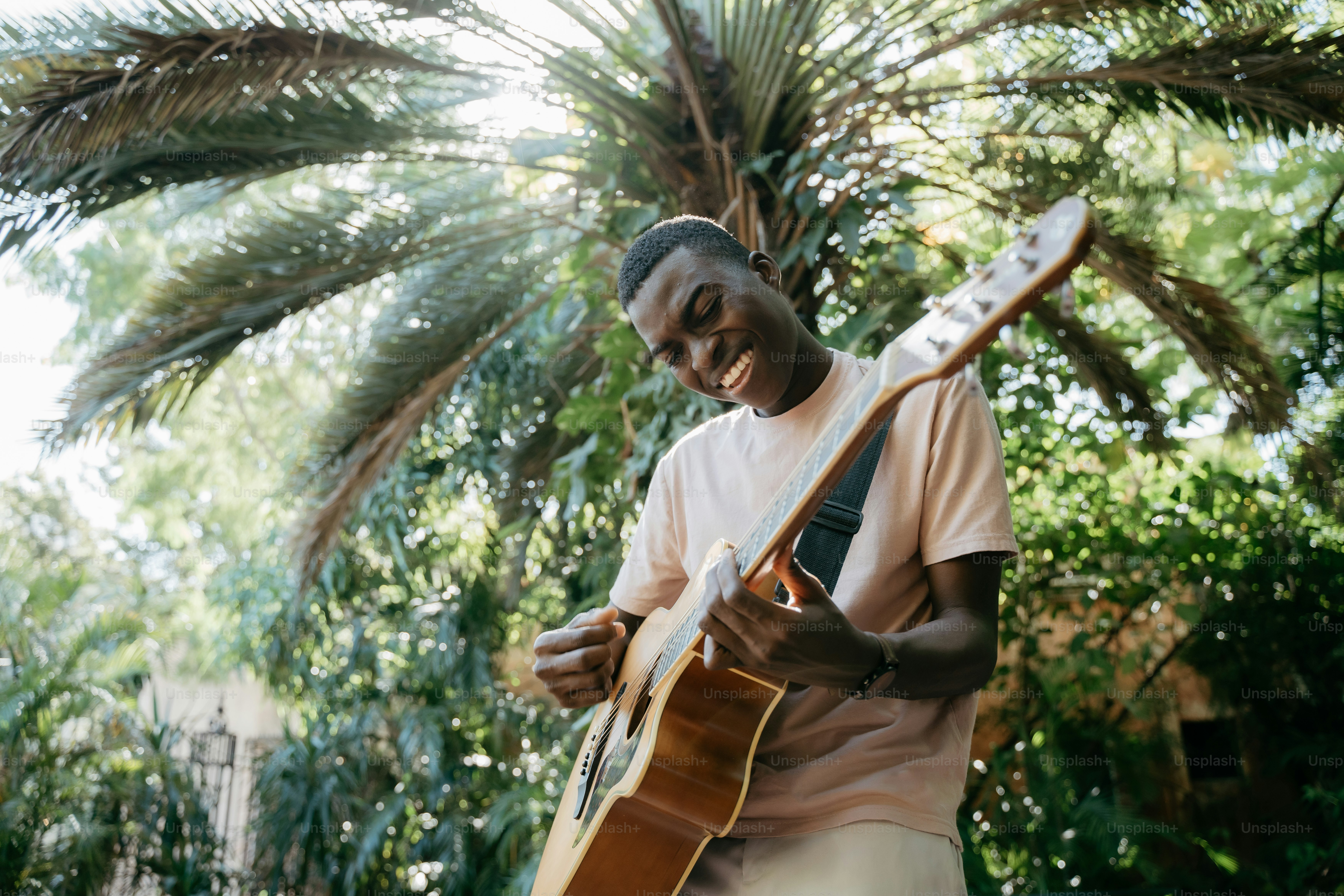 a man playing a guitar in front of a palm tree